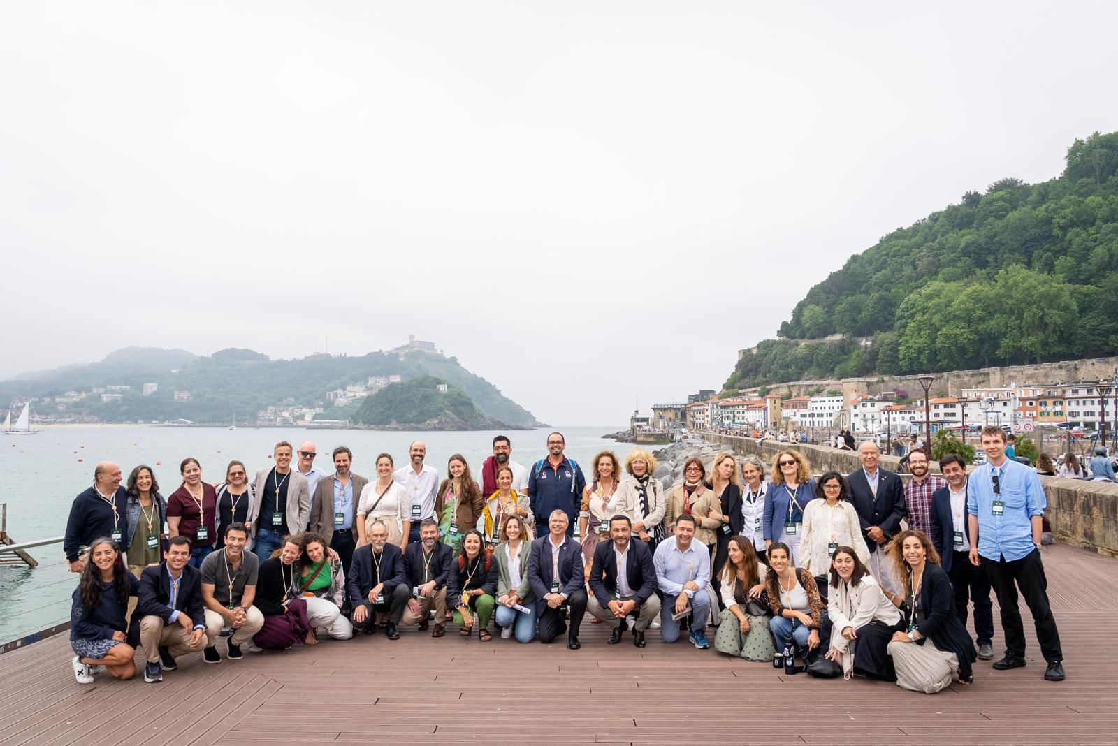 Personas posando con el mar a sus espaldas en un encuentro global.