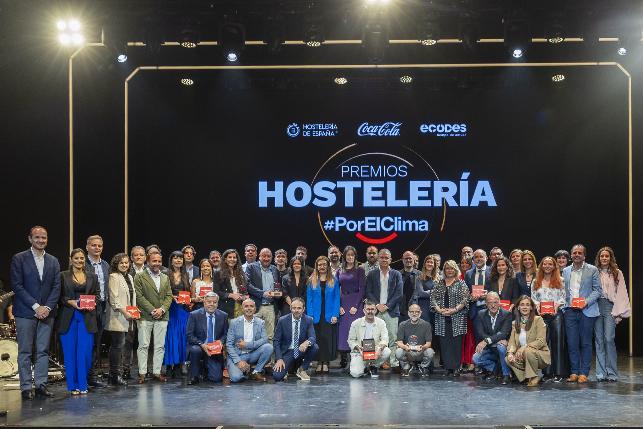 Grupo grande de personas posando con un premio en un escenario.
