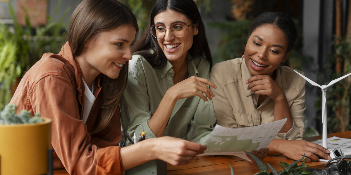 Tres chicas sentadas en un sofá mirando una hoja con datos